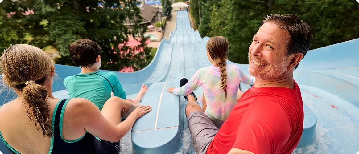 A man taking a selfie at the top of a water slide with his daughter